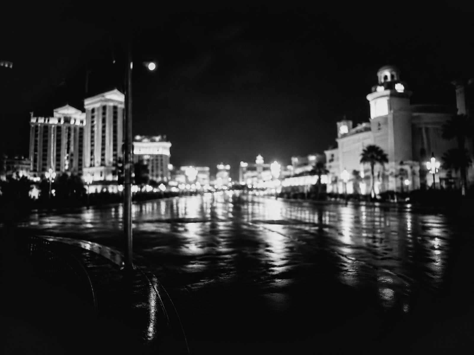 Archival black-and-white photograph of a rain-slicked Las Vegas boulevard at night